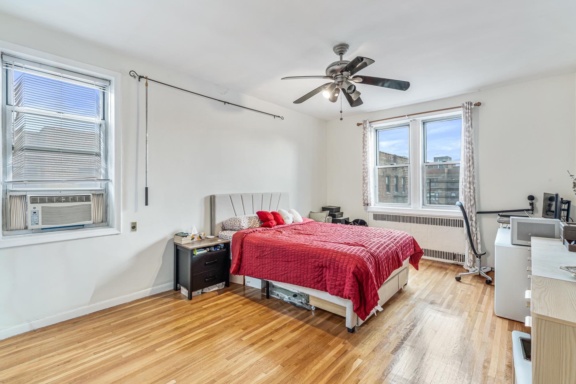 Spacious bedroom with hardwood floors and two windows in a Rego Park, Queens NY co-op for sale at 65-74 Saunders Street 6J — Homes by Agatha